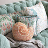 Decorative pillows on a mint green sofa with a neutral background