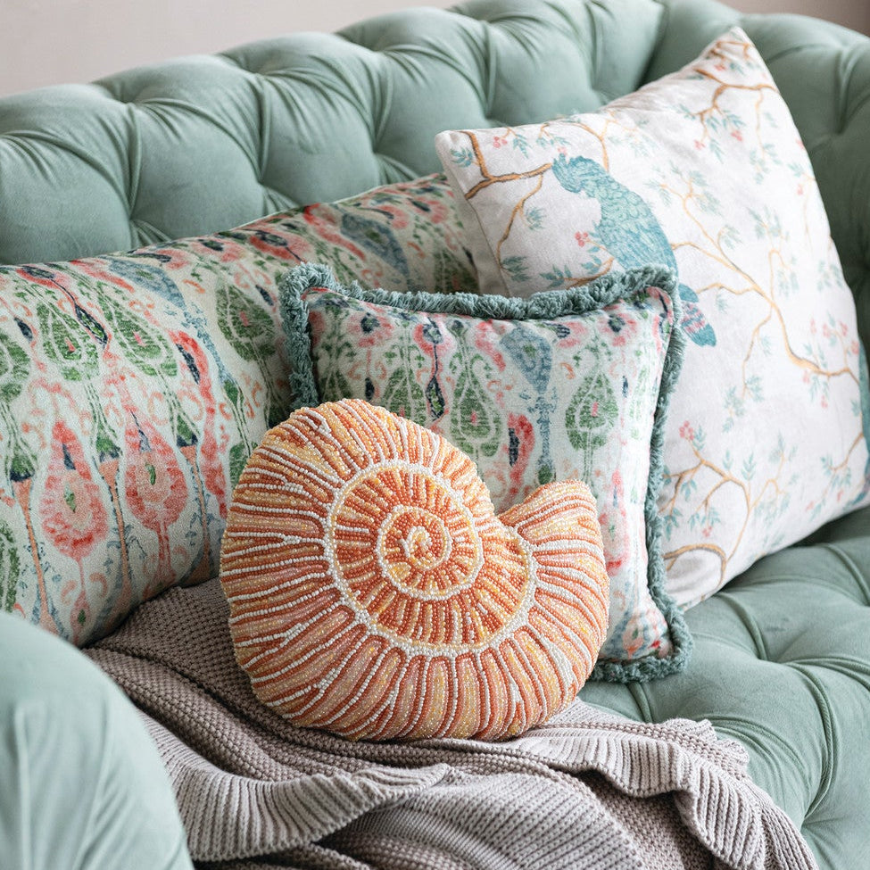Decorative pillows on a mint green sofa with a neutral background