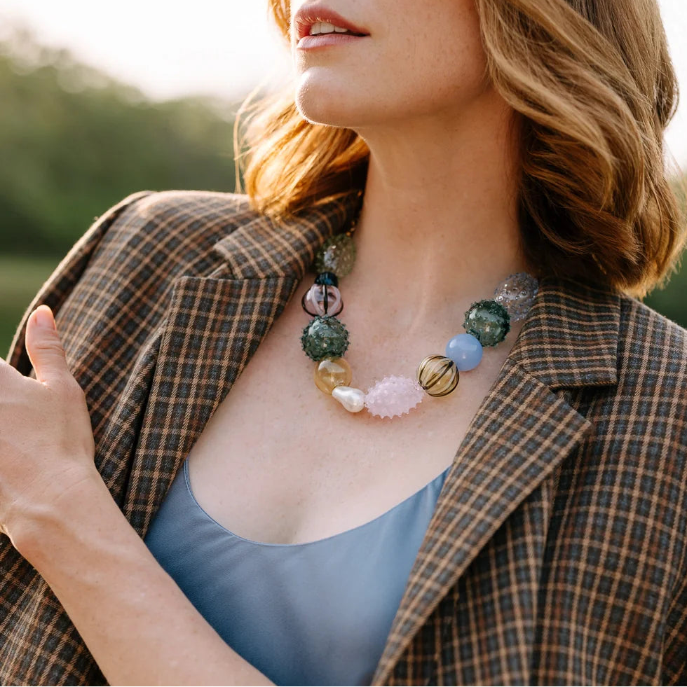 Woman wearing a plaid jacket and colorful necklace outdoors