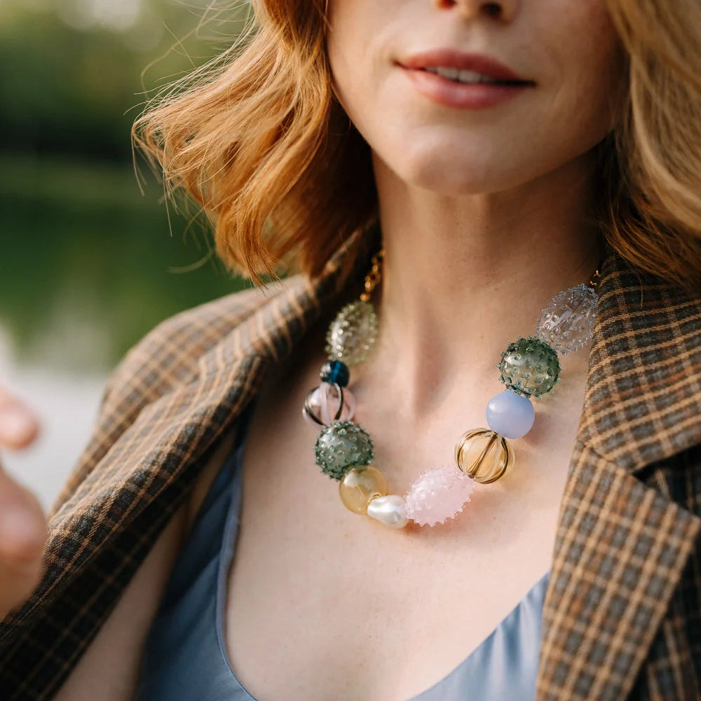 Woman wearing a colorful necklace with a blurred natural background