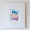 A framed abstract artwork featuring blue, pink, gold, and purple, presented in a white mat and a thin gold frame against a white wall.